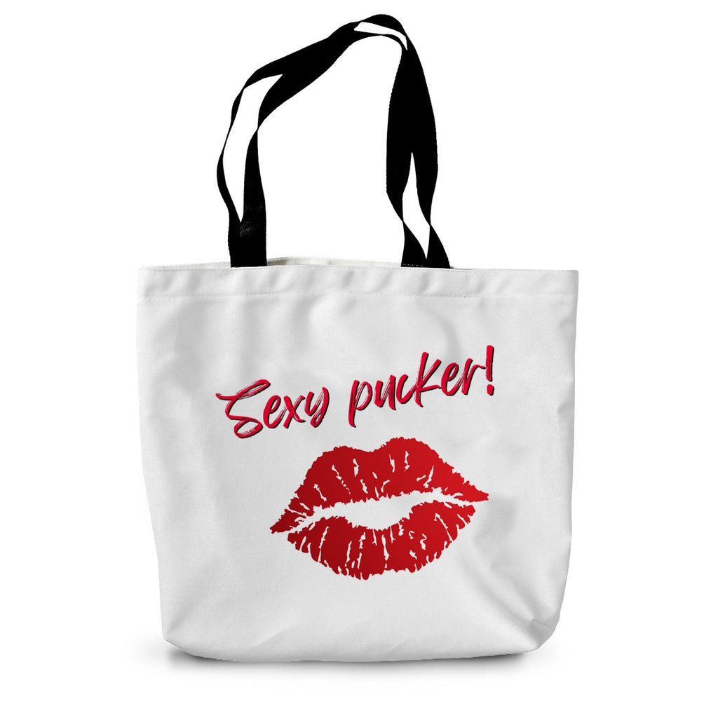A white canvas tote bag with long black handles. Bright red lips and the words Sexy Pucker! are on the side.