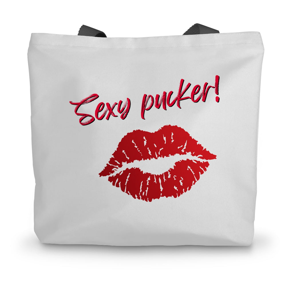 A white canvas tote bag with black handles. Bright red lips and the words Sexy Pucker! are on the side.